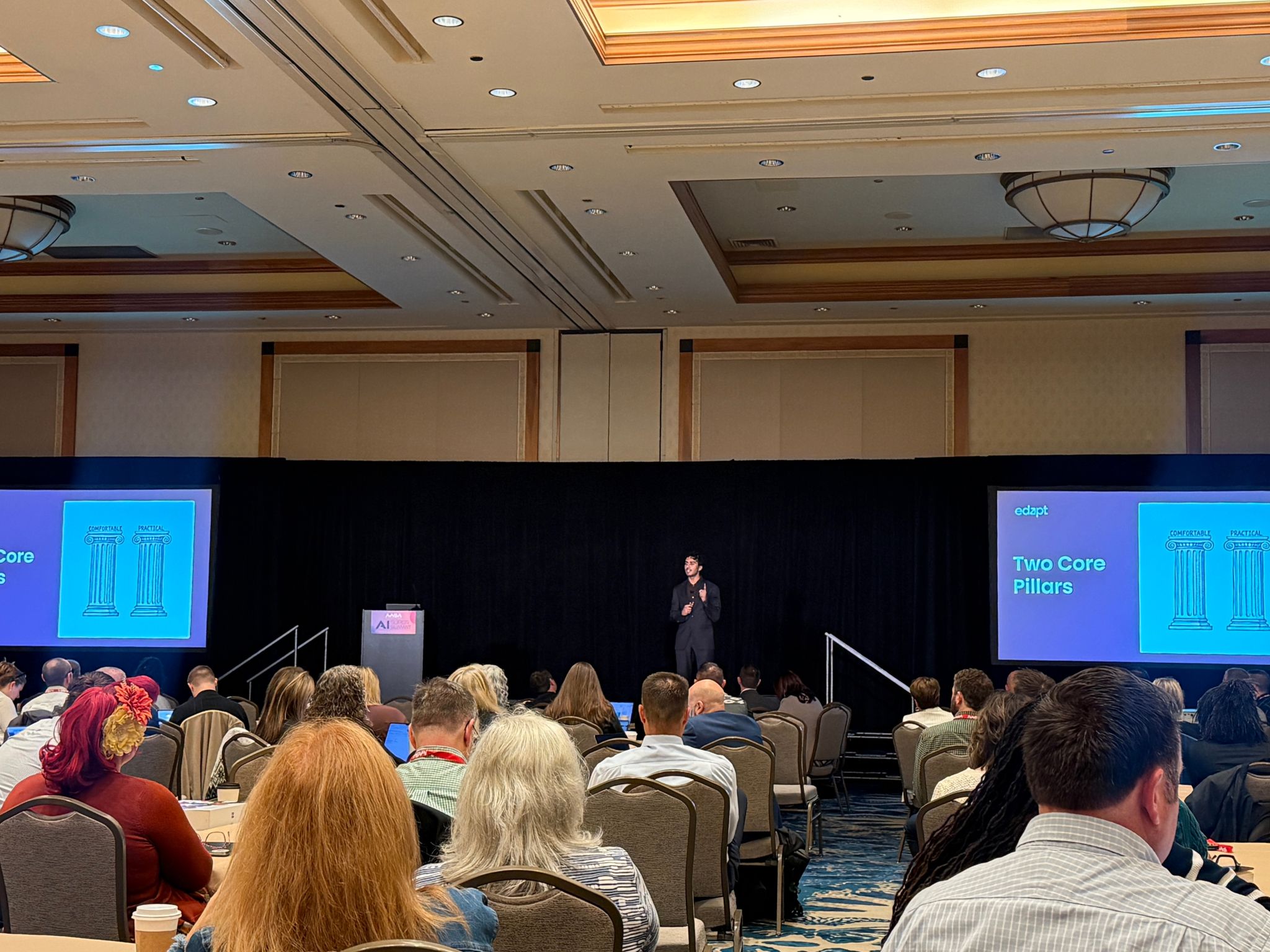 Christian Jackson presenting on a ballroom stage with dual screens